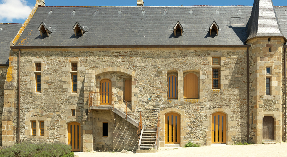 Grange médiévale en pierre avec toit en ardoise.