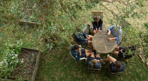 Personnes assises autour d'une table en bois, extérieur.