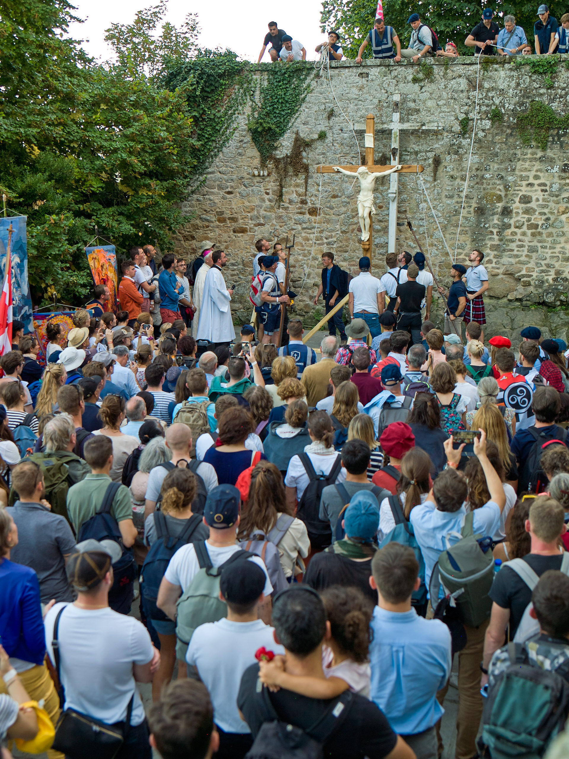 Procession religieuse avec une grande foule et croix.