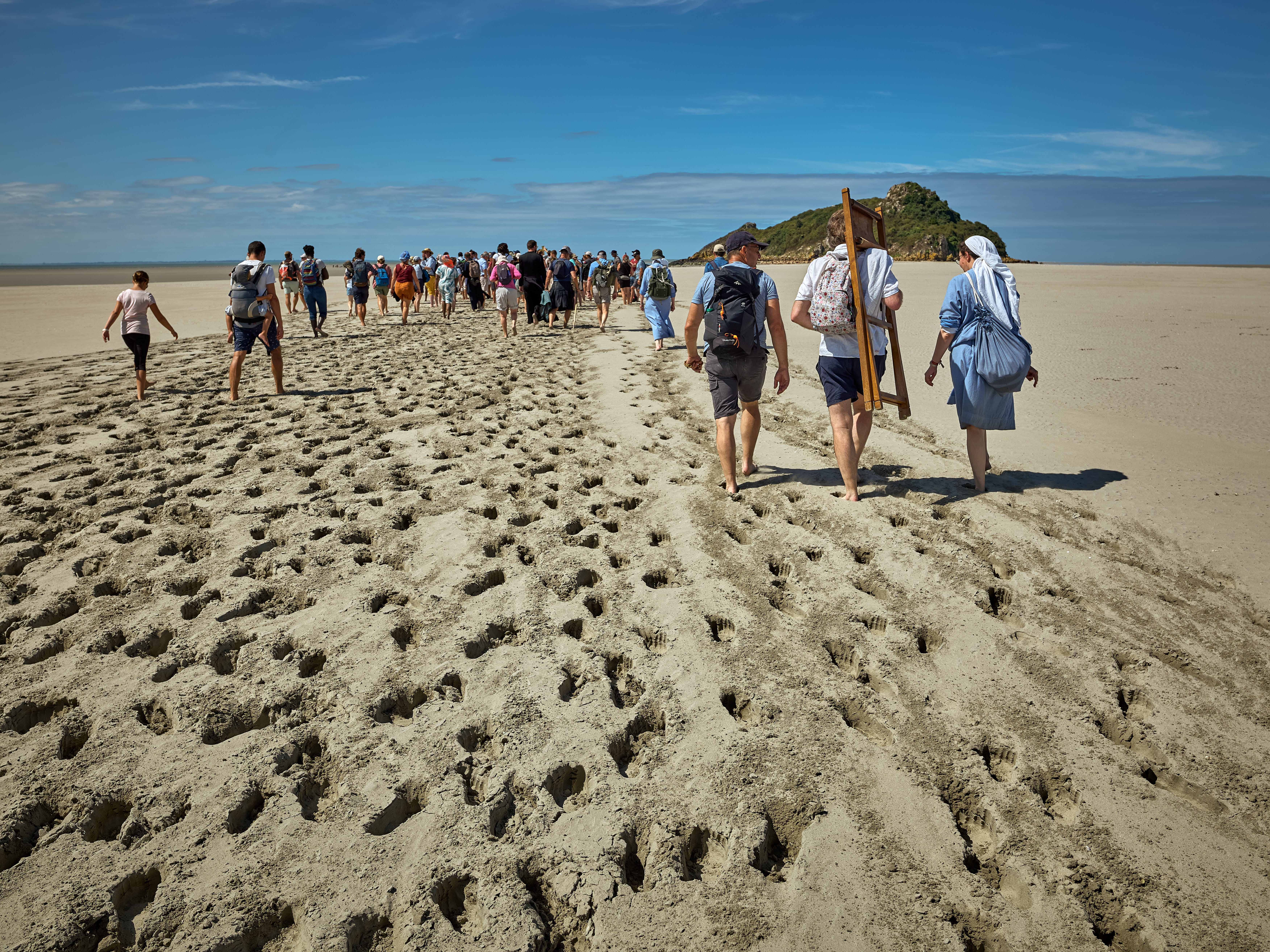 Groupe marchant sur du sable vers une île.