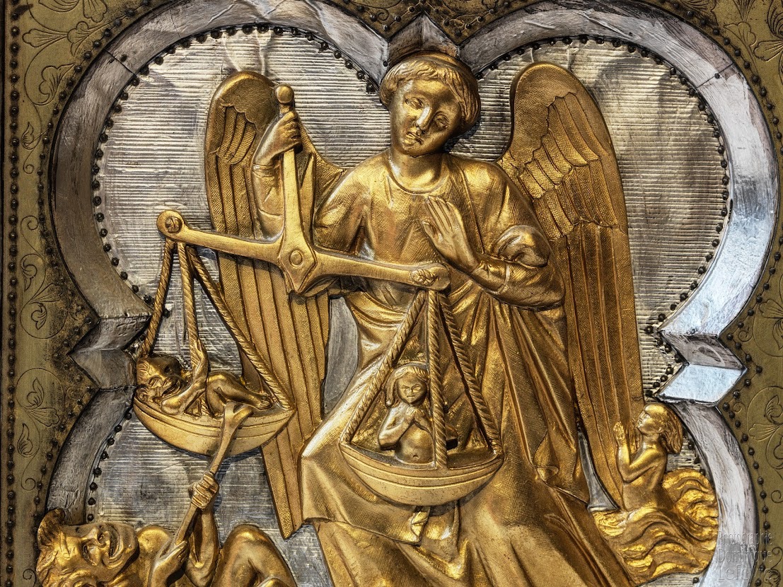 Ange doré pesant les âmes sur une balance.