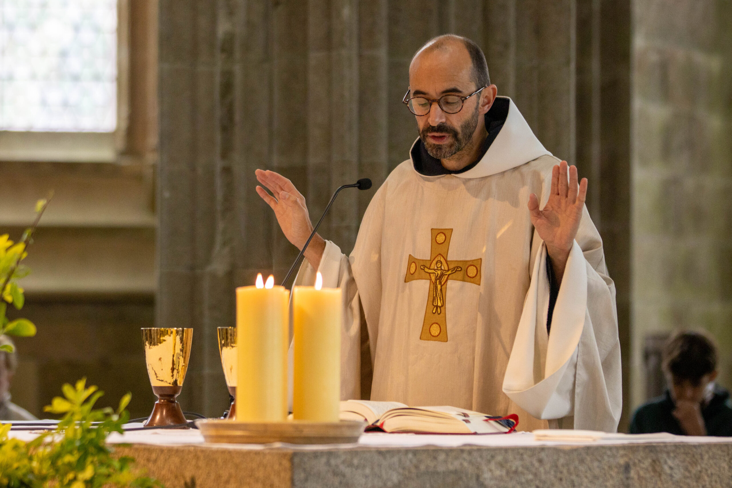Prêtre célébrant la messe avec calices et bougies.