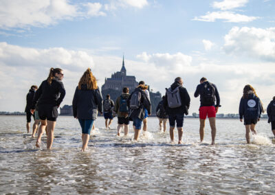 Groupe marchant vers Mont Saint-Michel dans l'eau.