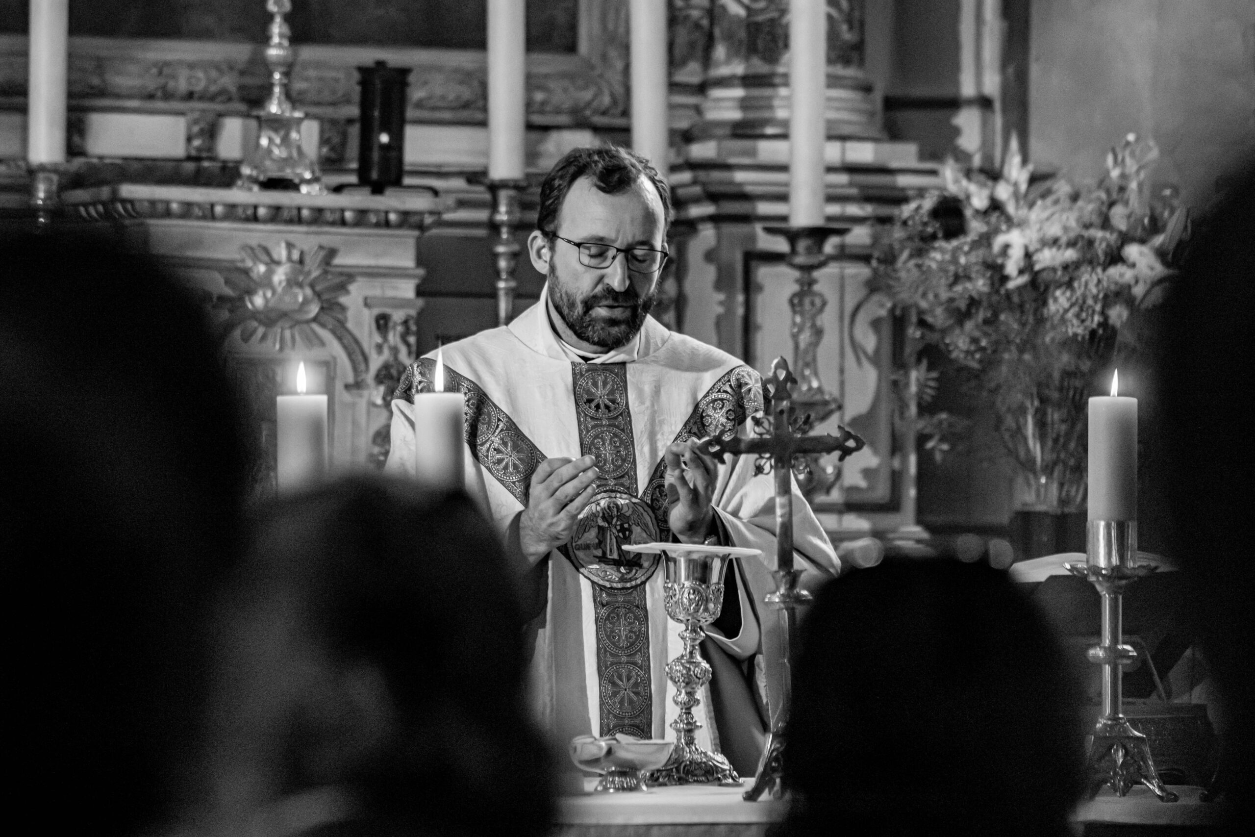 Prêtre célébrant messe avec calice et crucifix.