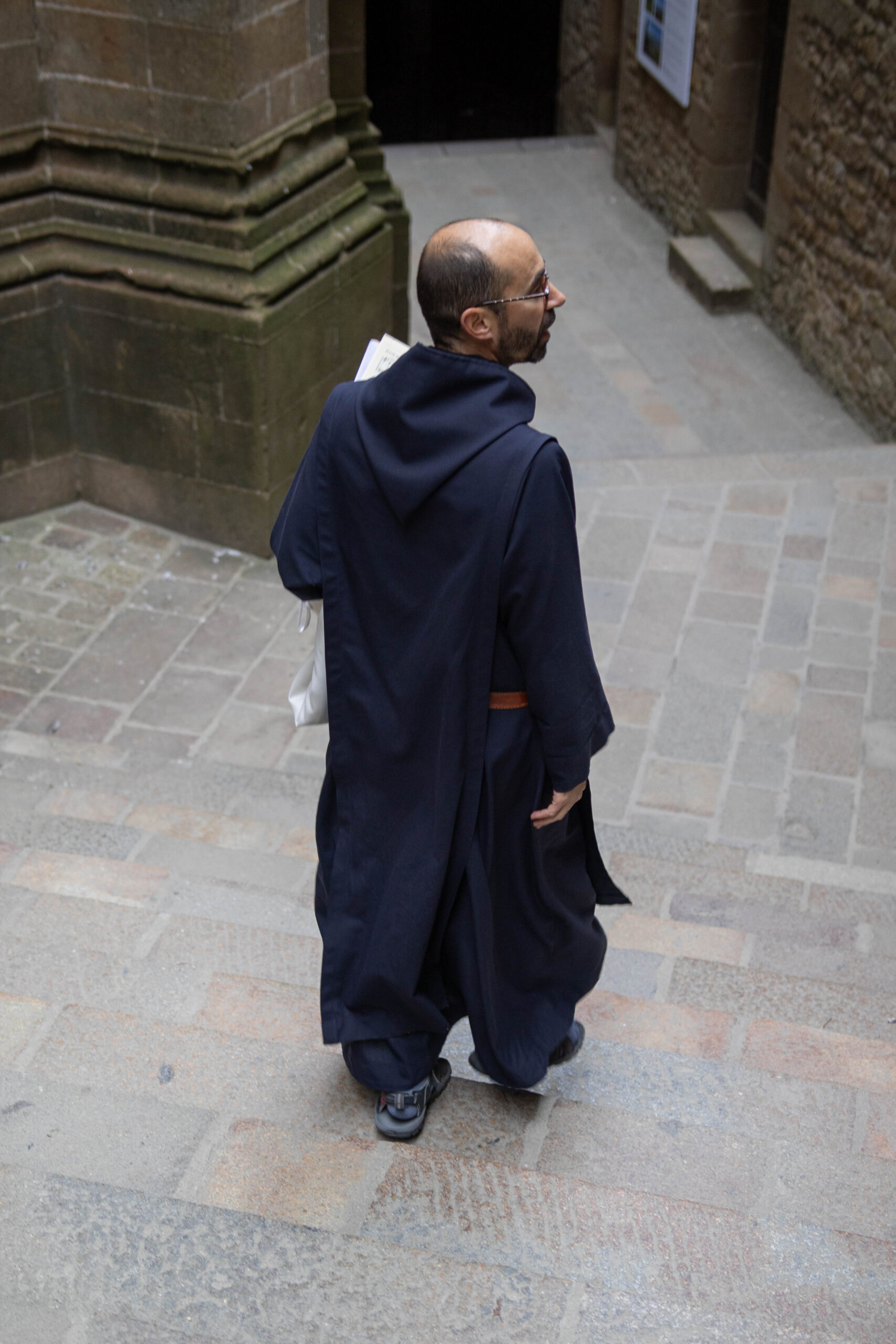 Moine descendant des escaliers en robe sombre.